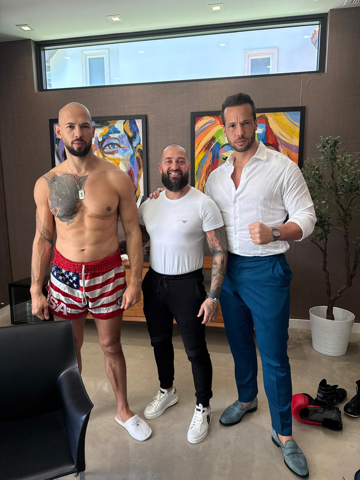 Archive photograph of Andrew Tate (left), Gabriel Ernesto Rapisarda (center), and Tristan Tate (right) in September 2025. Black rectangles cover the Tate brothers' eyes.